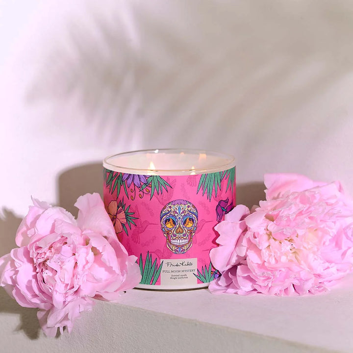 Frida Kahlo “Full Moon Mystery” scented candle with three wicks, featuring a vibrant pink label decorated with tropical leaves, flowers, and a colorful sugar-skull design.