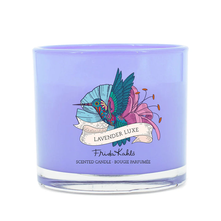 Frida Kahlo Lavender Luxe scented candle.  Elegant purple glass candle featuring a colorful hummingbird and floral design on the front.
