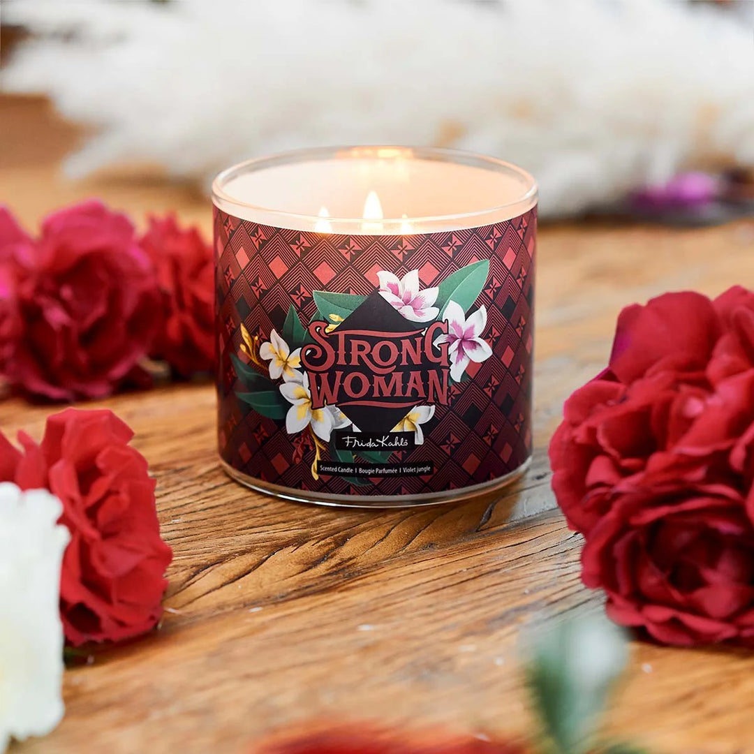 Frida Kahlo “Strong Woman” scented candle with rose-gold lid and bold burgundy geometric label featuring tropical flowers. 
