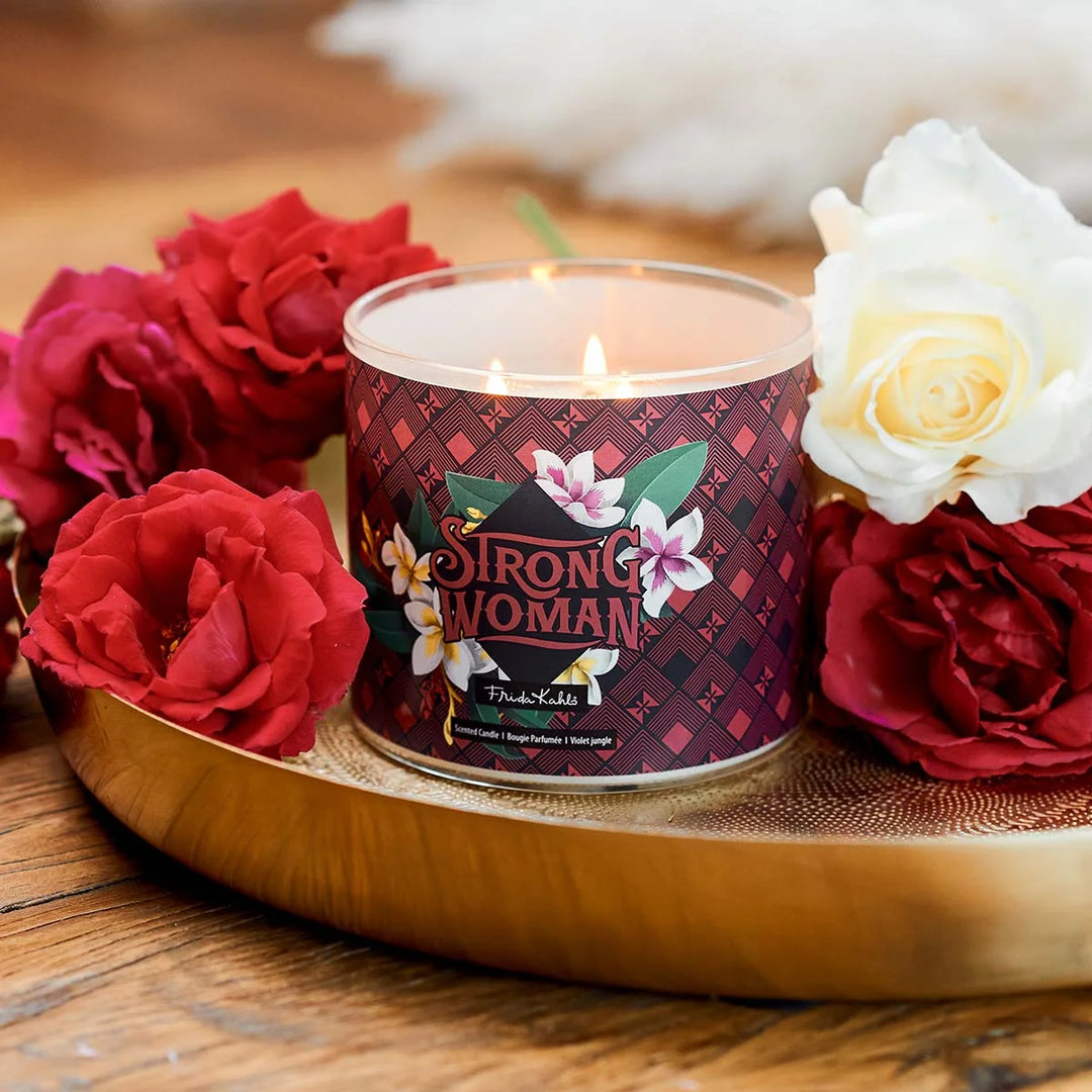 Frida Kahlo “Strong Woman” scented candle with rose-gold lid and bold burgundy geometric label featuring tropical flowers. 