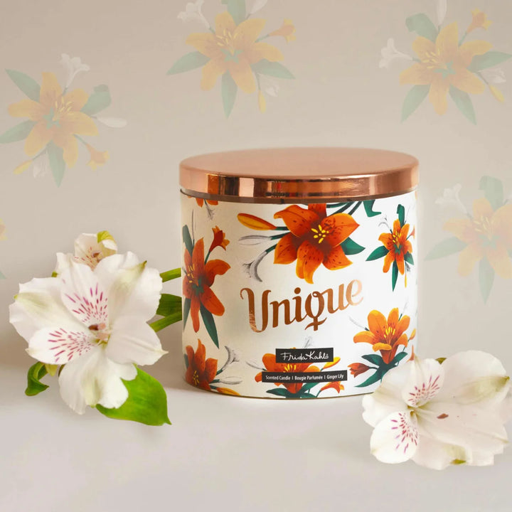 Frida Kahlo “Unique” scented candle with a rose-gold lid and floral ginger lily design. Decorative premium candle featuring vibrant orange lilies, perfect for home fragrance, gifting, and stylish interior décor.