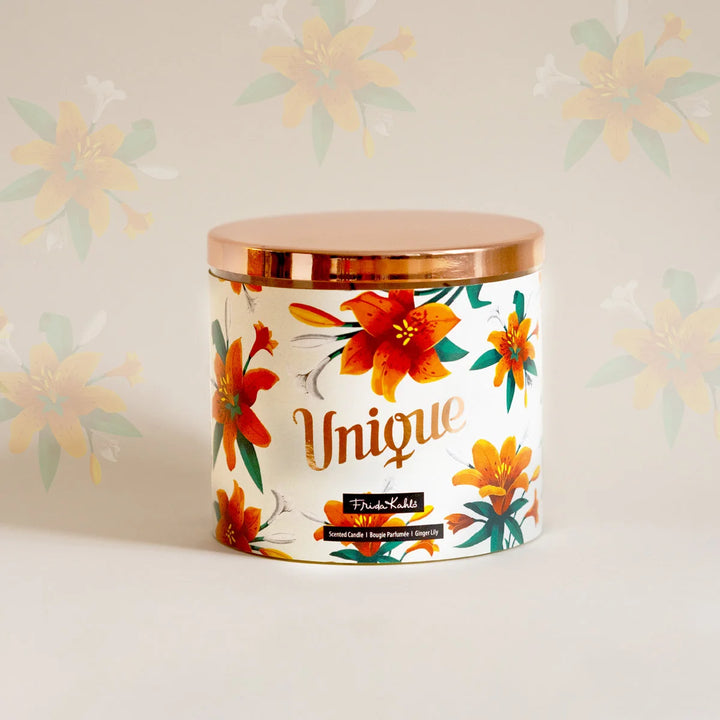Frida Kahlo “Unique” scented candle with a rose-gold lid and floral ginger lily design. Decorative premium candle featuring vibrant orange lilies, perfect for home fragrance, gifting, and stylish interior décor.