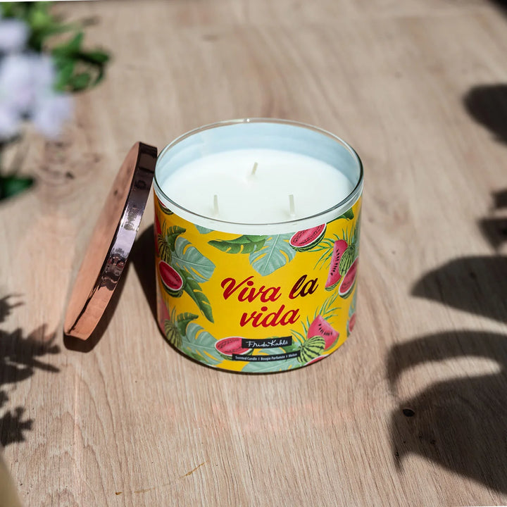 Frida Kahlo “Viva la Vida” scented candle with rose-gold lid and vibrant yellow label featuring watermelon and tropical leaf illustrations. 