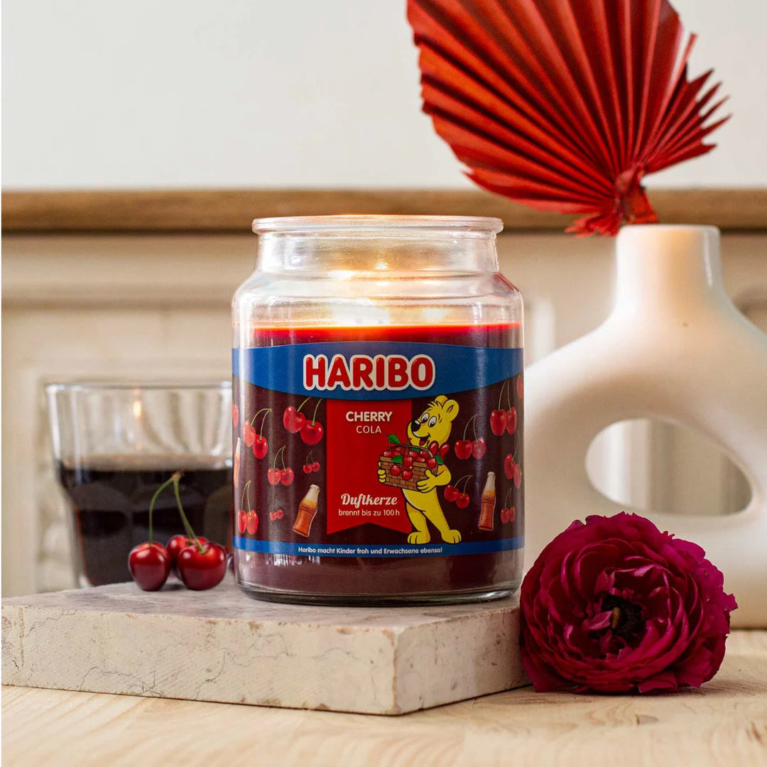 Haribo Cherry Cola Scented Candle in glass jar with lit wick, red wax and cherries and cola design label