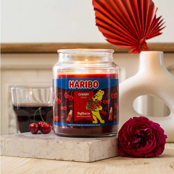 Haribo Cherry Cola Scented Candle in glass jar with lit wick, red wax and cherries and cola design label
