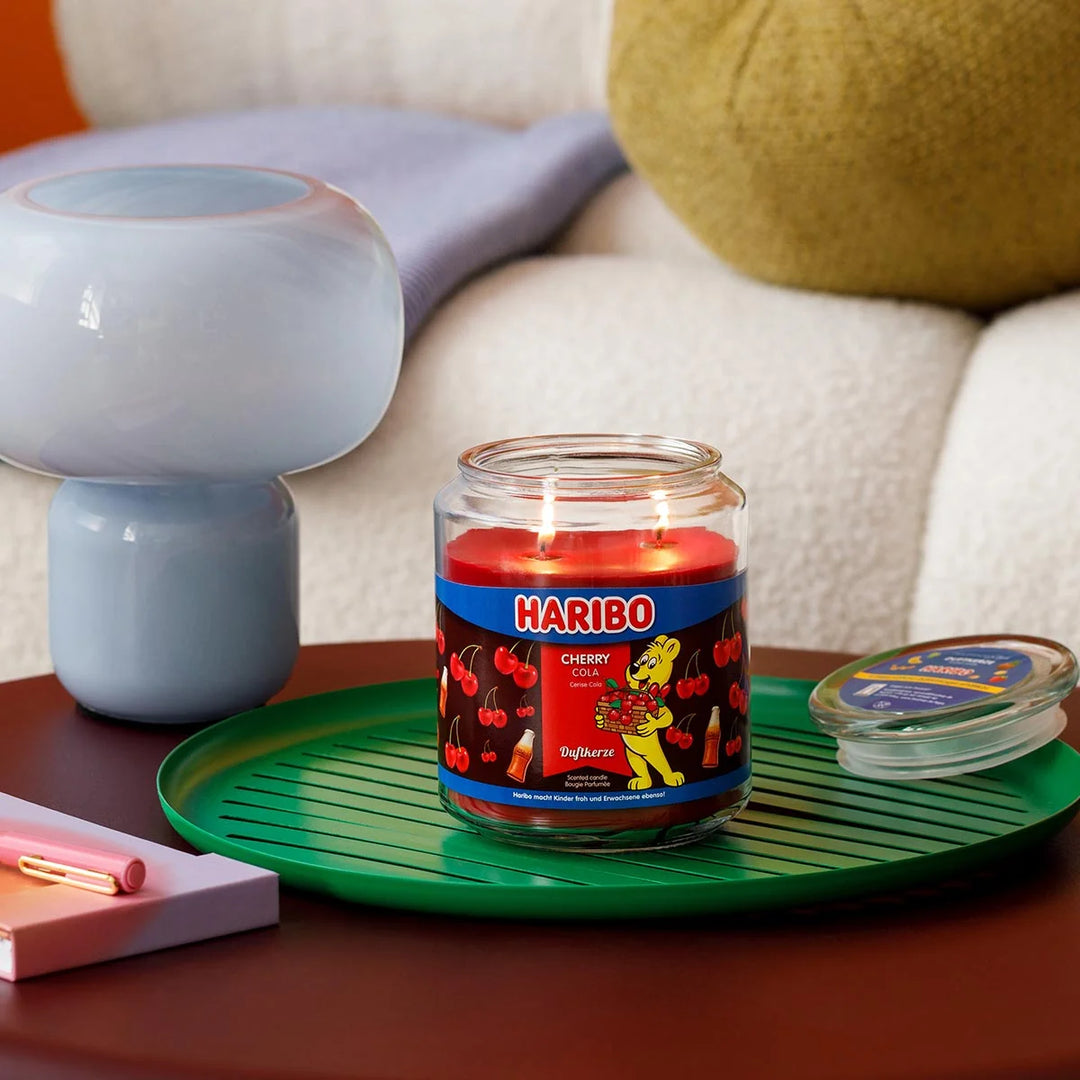 Haribo Cherry Cola Scented Candle in glass jar with lit wick, red wax and cherries and cola design label