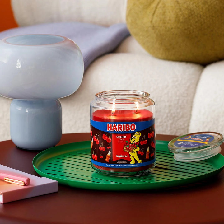 Haribo Cherry Cola Scented Candle in glass jar with lit wick, red wax and cherries and cola design label