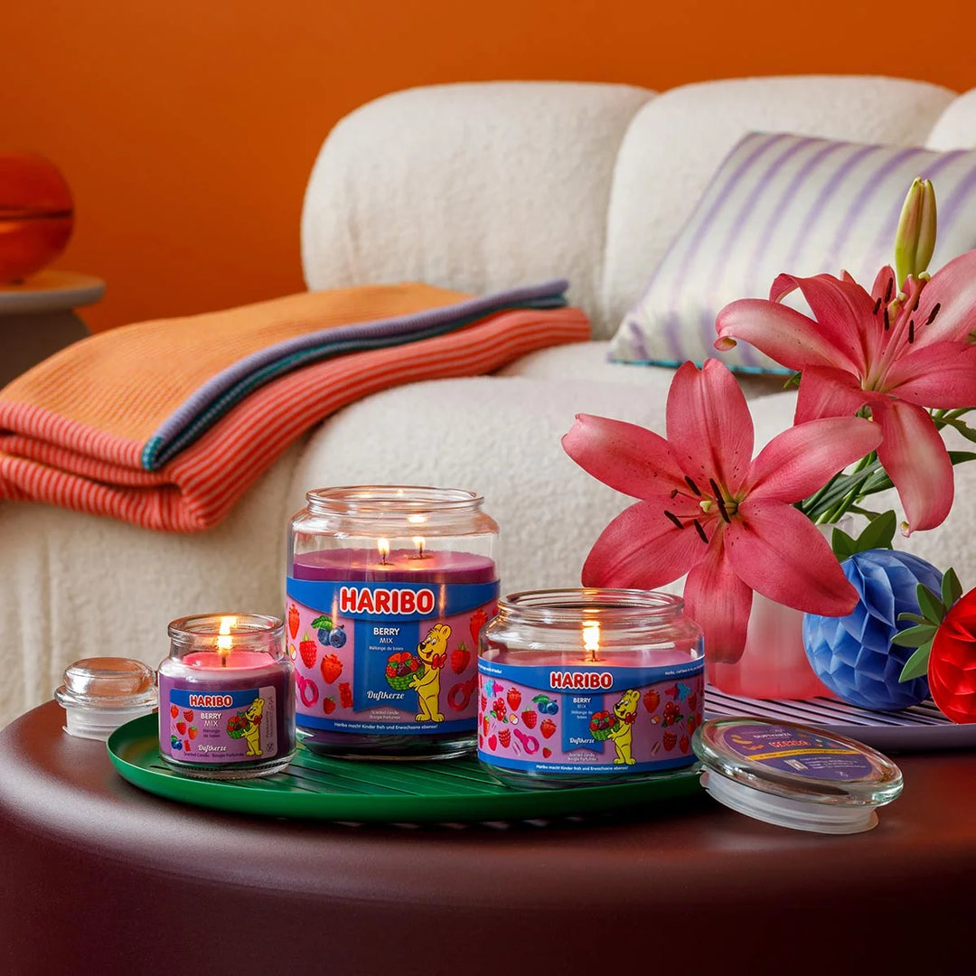 Haribo Berry Mix Scented Candle in glass jar with lit wick, purple wax and berries design label