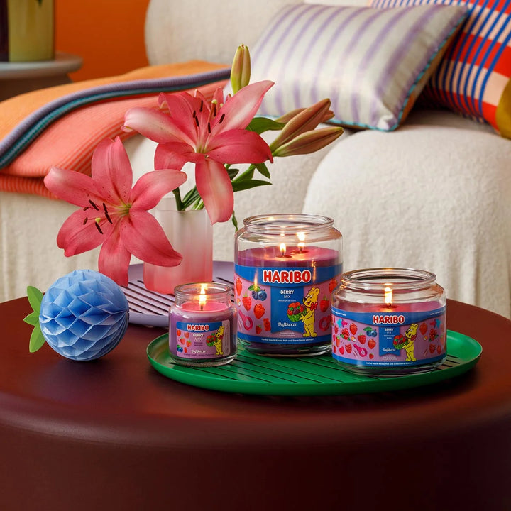 Haribo Berry Mix Scented Candle in glass jar with lit wick, purple wax and berries design label