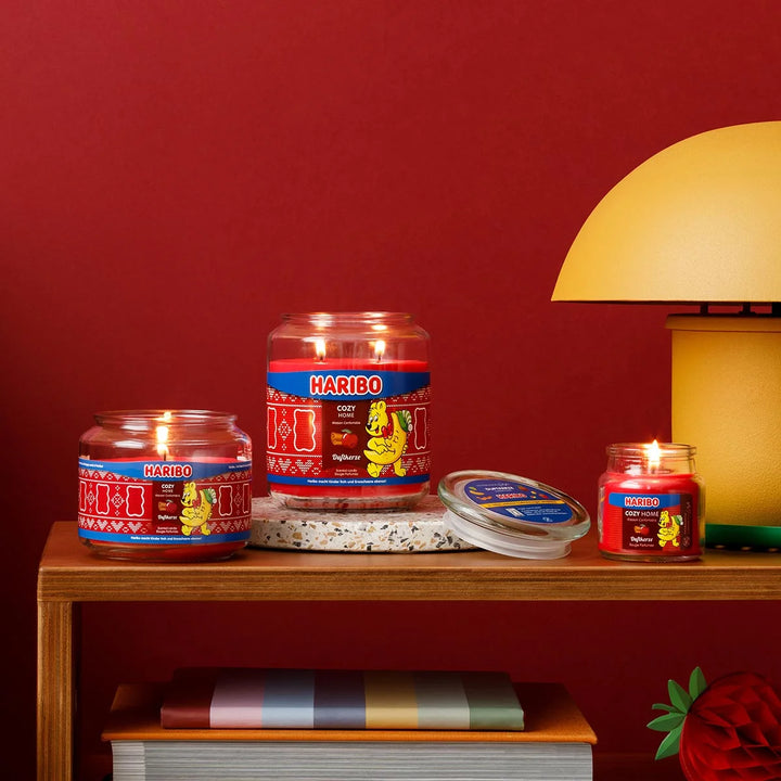 HARIBO Cozy Home scented candle – red jar candle decorated with apple, cinnamon, and the cheerful HARIBO bear holding a moon.