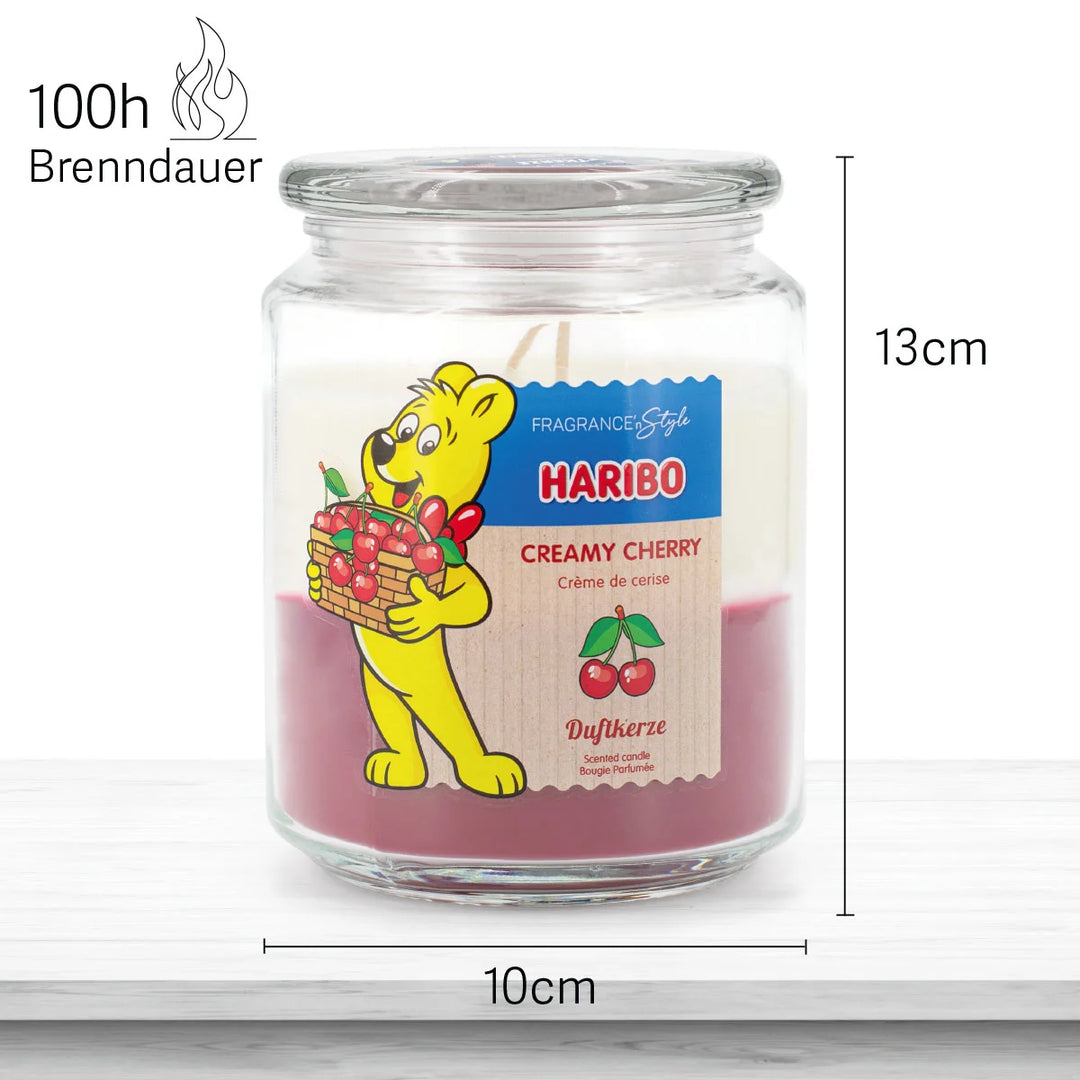 HARIBO Creamy Cherry scented candle in a glass jar with white and red wax featuring the Haribo bear holding a basket of cherries.