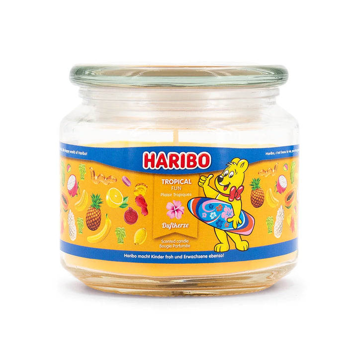 Haribo Tropical Fun Scented Candle in glass jar with lit wick, orange wax and  and fruits design label